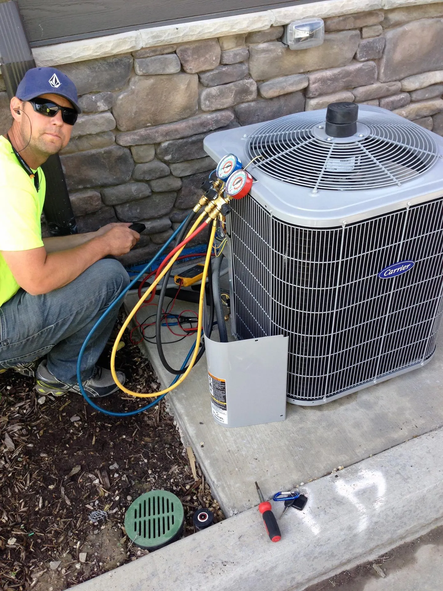 AYSP technician with manifold gauges on a Carrier AC condenser